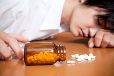 Asyalı adam intihar etmek için bir sürü hap alıyor.