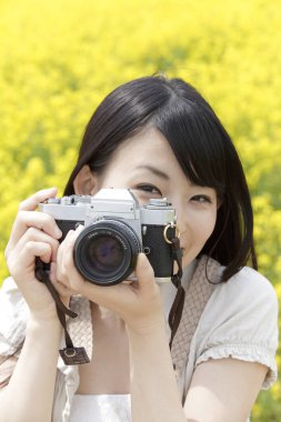 Kırsalda kamerayla fotoğraf çeken genç bir kadın..