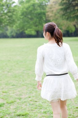 Parkta yürüyen Asyalı kadın.