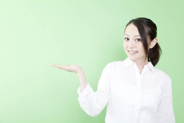 Asyalı kadın yeşil arka planda açık avuç içi gösteriyor. 