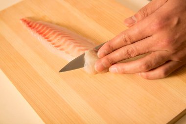 Şef bir parça çiğ balığı bıçakla keser.