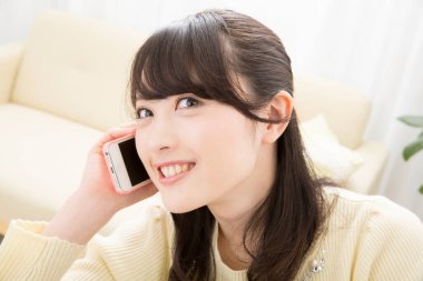 Akıllı telefondan konuşan gülümseyen Asyalı kadın, yakın plan portre 