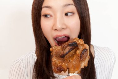 Asyalı kadın ızgara tavuk yiyor.