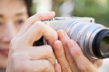 Kıdemli Asyalı kadın kamerasıyla fotoğraf çekiyor.