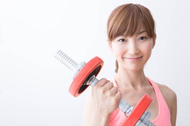 Spor yapan genç bir kadın dambılı giyiyor.