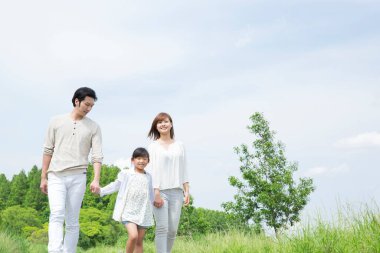 Mutlu bir aile yazın parkta yürüyor.