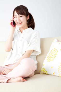 Evde cep telefonu kullanan Asyalı kadın. 