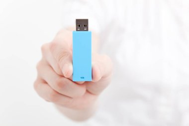 Ayrı bir arkaplanda mavi bir USB çubuğu tutan el..