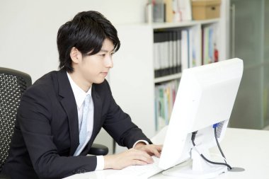 Genç adam ofiste bilgisayarla çalışıyor.