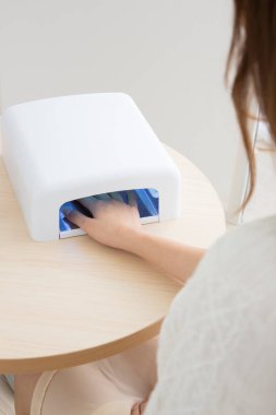 UV tırnak kurutma makinesi kullanan bir kadın.