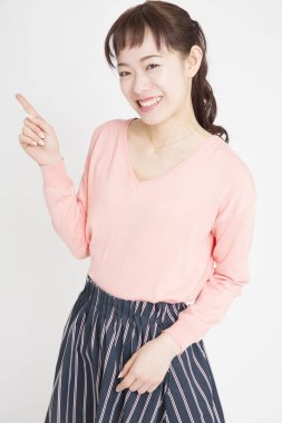 Beyaz arka planda parmağı olan Asyalı genç bir kadının portresi.