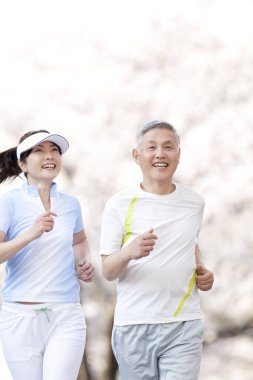 Asyalı olgun çift parkta koşuyor.