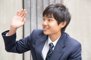 Asyalı öğrenci el sallıyor.