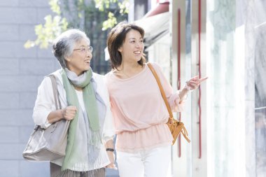 Bir kadın sokakta büyük annesine bir şey gösteriyor. 