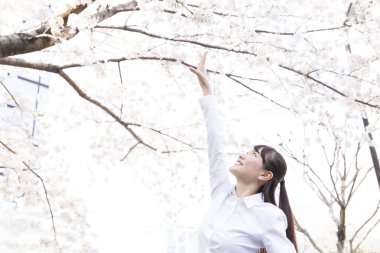 Parkta çiçek açan bir ağacı olan genç bir kadın.