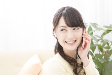 Akıllı telefondan konuşan gülümseyen Asyalı kadın, yakın plan portre 