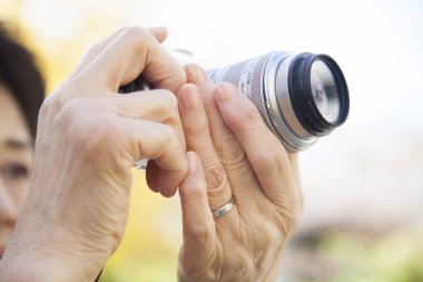 Kıdemli Asyalı kadın kamerasıyla fotoğraf çekiyor.