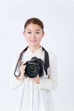 Kamerayla poz veren genç Asyalı kadın fotoğrafçı