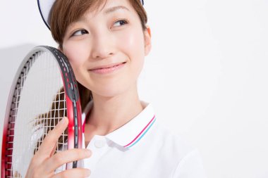 Beyaz stüdyo arka planında tenis oynayan Asyalı kadın