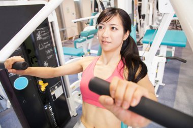 Güzel genç Asyalı kadın spor salonunda egzersiz yapıyor.