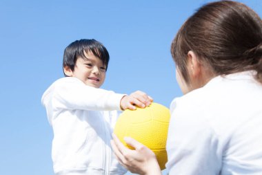 Asyalı anne ve oğlu parkta top oynarken yakınlaşın.