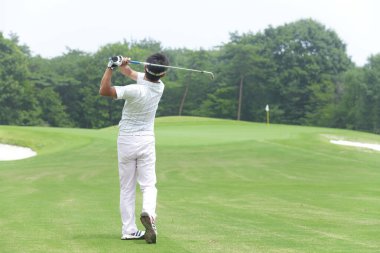 Genç Japon adam gündüz golf oynuyor. 