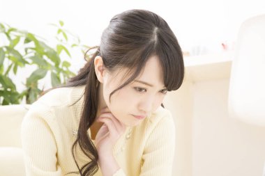 Genç Asyalı kadın evde düşünüyor.