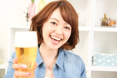 Neşeli Japon kadın evde bira içiyor.