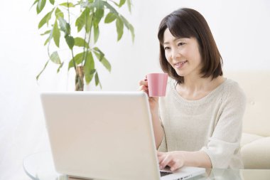 Laptoplu Asyalı kadın çay içiyor.