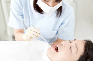 Kadın dişçi hasta dişlerini muayene ediyor. 