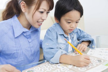 Küçük Asyalı çocuk annesiyle resim çiziyor.