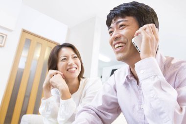 Genç adam ve kadın telefonda konuşuyor.