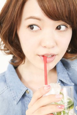 Güzel genç Japon kadının portresi ferahlatıcı bir içecek içiyor.