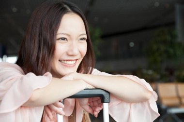 Havaalanı terminalinde bavullu güzel bir Japon kadın. seyahat ve tatil kavramı