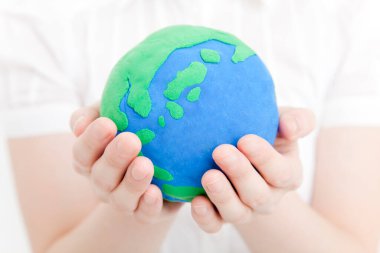 Kadın elleri arka planda dünyayı tutuyor.