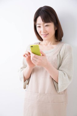 Mutlu genç Asyalı kadın cep telefonu kullanıyor.