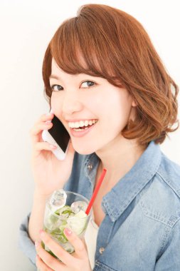 Elinde içki tutan ve telefonla konuşan güzel bir Japon kadının portresi.