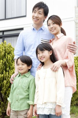 Dört kişilik aile evinin yanında poz veriyor. 