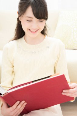 Evde kitap okuyan güzel Asyalı kadın