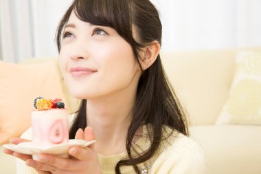 Güzel Asyalı kadın elinde lezzetli bir pasta tabağıyla