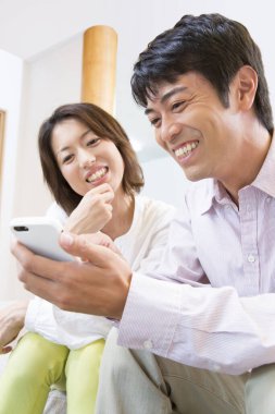 Evde cep telefonu kullanan Asyalı çift. 