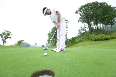Genç Japon adam gündüz golf oynuyor. 