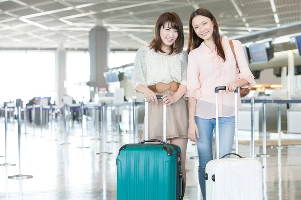 happy asian young women with luggage in airport