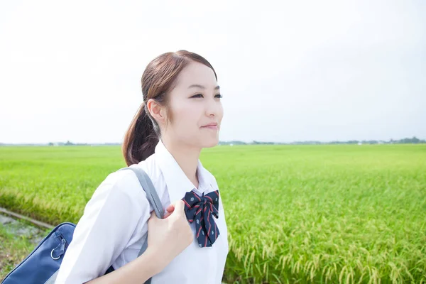 stock image smiling Asian schoolgirl walking with bag in the countryside