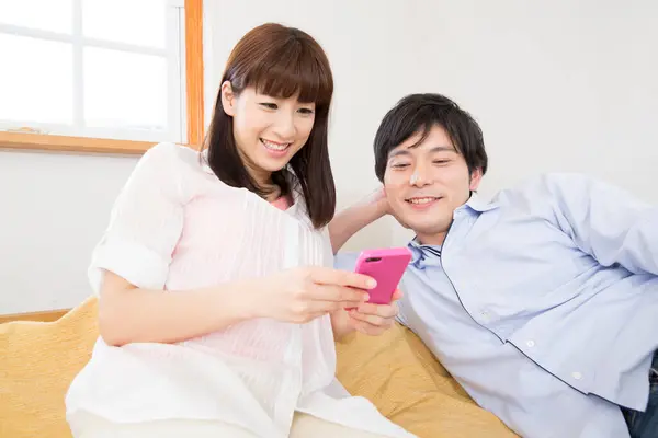 Mutlu Asyalı Çift Evde Akıllı Telefon Kullanıyor — Stok fotoğraf