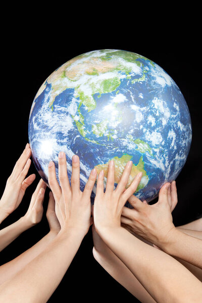 the human hands holding a globe on black background