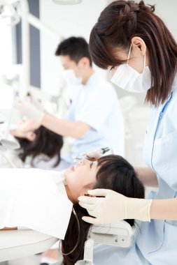 Asyalı erkek ve kadın dişçiler hastalarla çalışıyor 