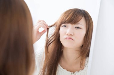 Uzun saçlı bir kadın aynada kendine bakıyor. 