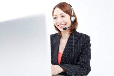 Bilgisayarda çalışan, kulaklıklı, gülümseyen genç bir kadının portresi. 