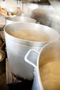 Endüstriyel mutfakta büyük kaplar kaynıyor.